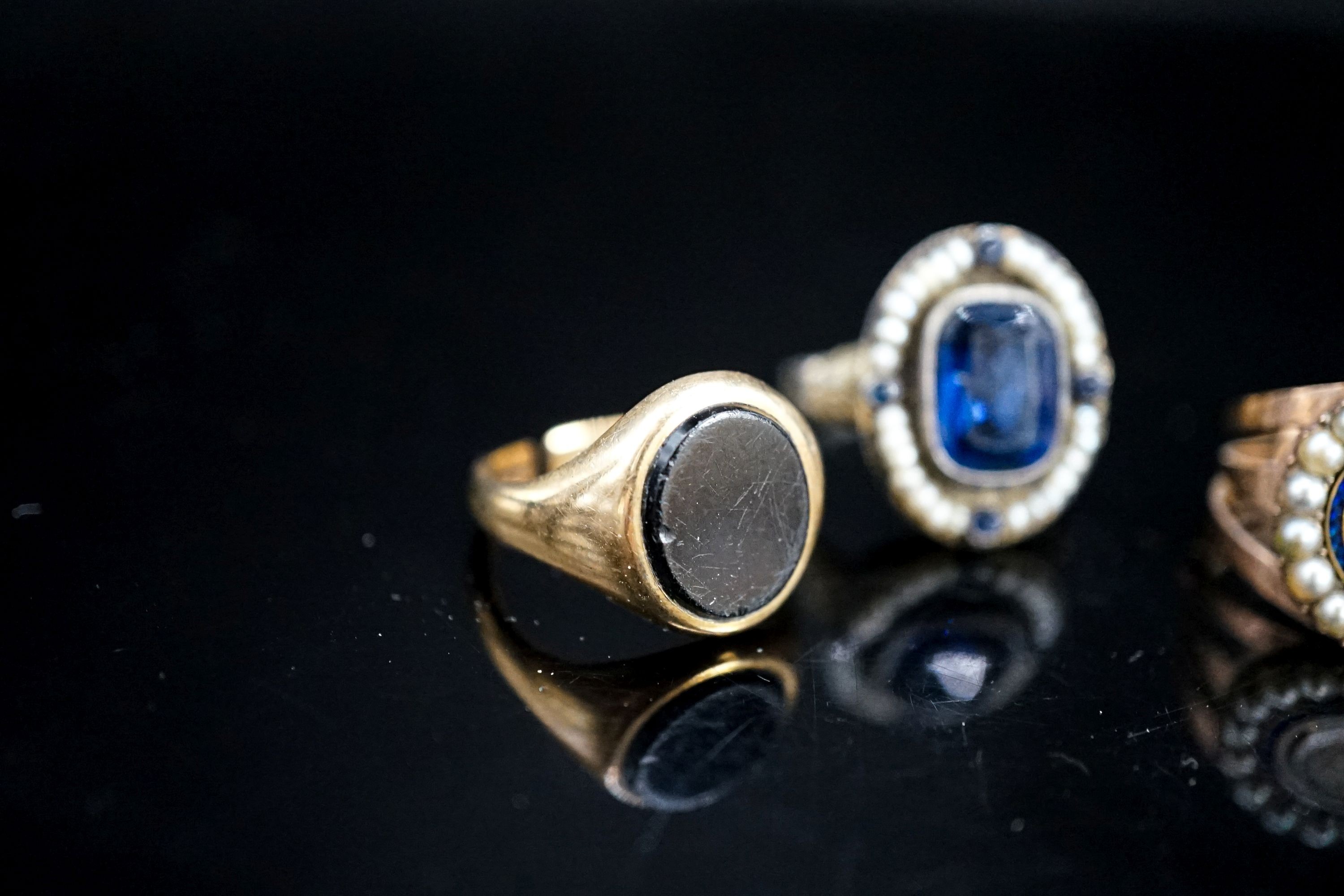 A 19th century yellow metal, two colour enamel and seed pearl set mourning ring, with hair beneath a glazed panel, size N, a 19th century Austro-Hungarian white metal and blue paste ring and a later 9ct gold signet ring(